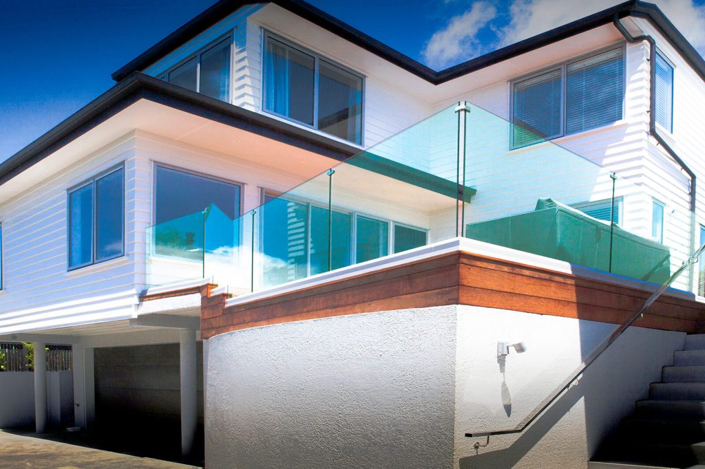 A modern house exterior featuring a frameless glass balustrade on a balcony, showcasing a clear view and stylish design.